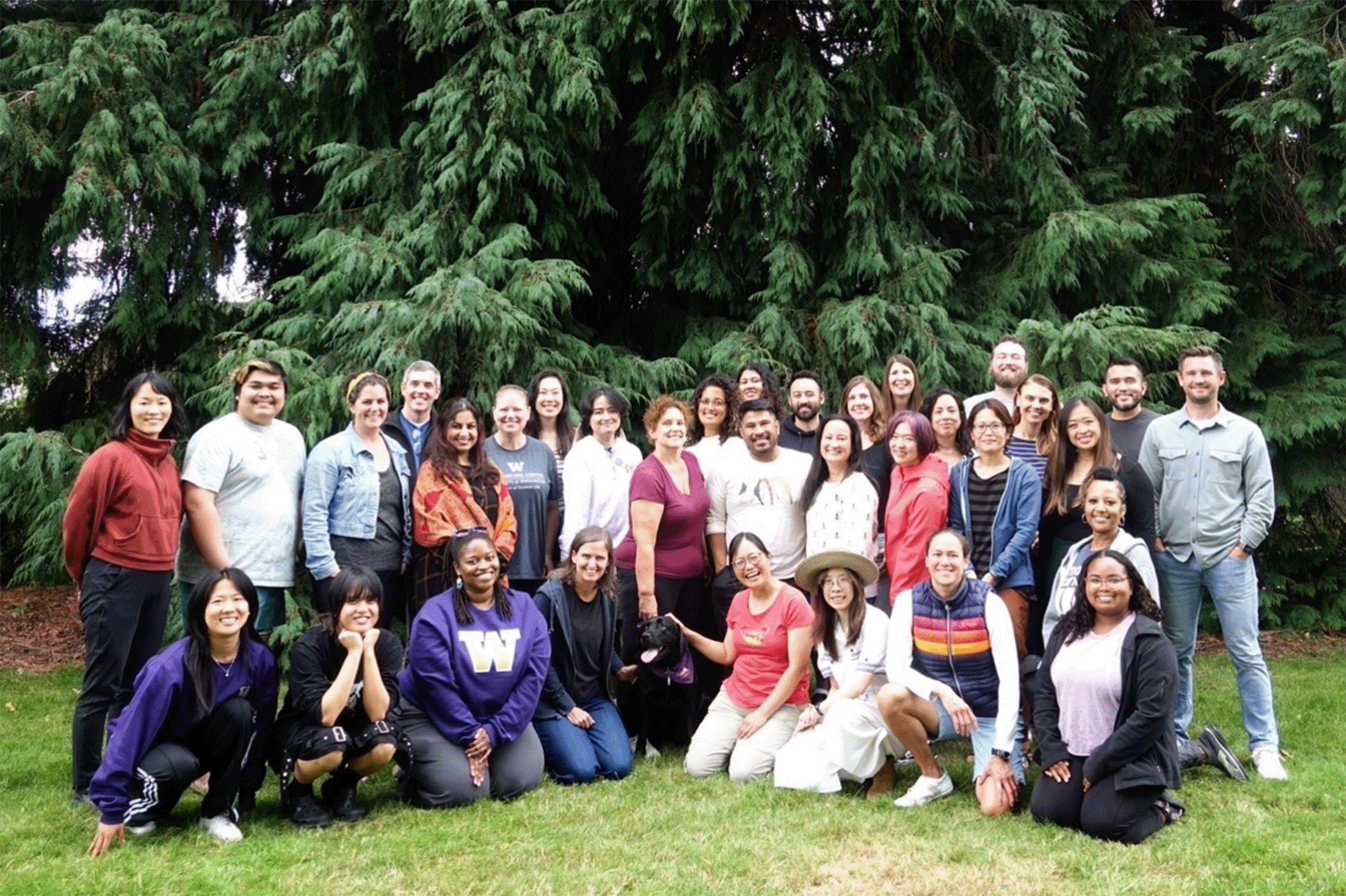 A photo of the Counseling Center Staff of 2024-2025. The group is smiling at the camera standing in front of green trees.