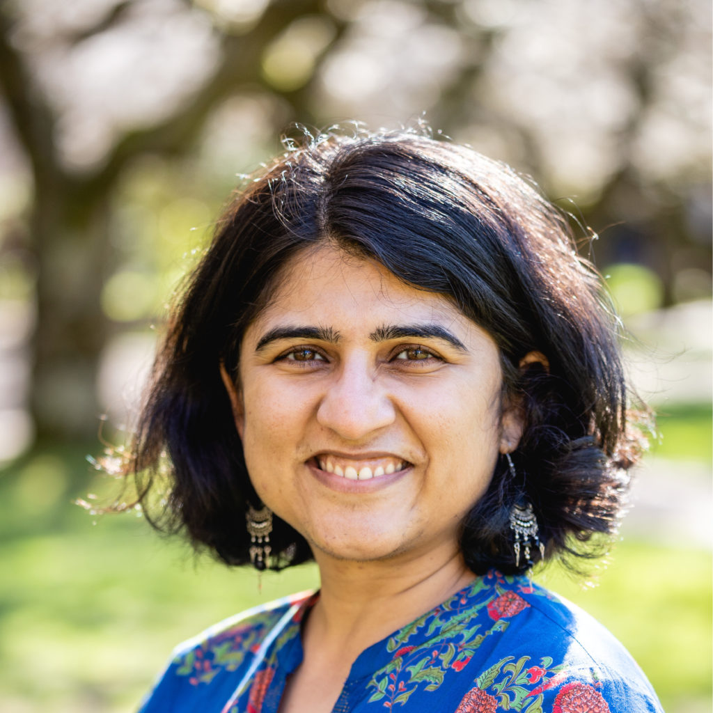 A smiling photo of Dr. Gitika Talwar, Hall Health. Gitika has short black hair and is wearing a blue floral top.