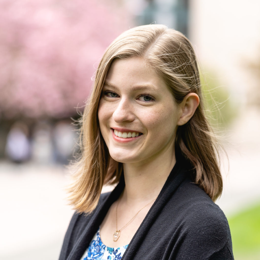 A smiling photo of Katie Gallagher SafeCampus. Katie has medium blonde hair and is wearing a blue top with black jacket.