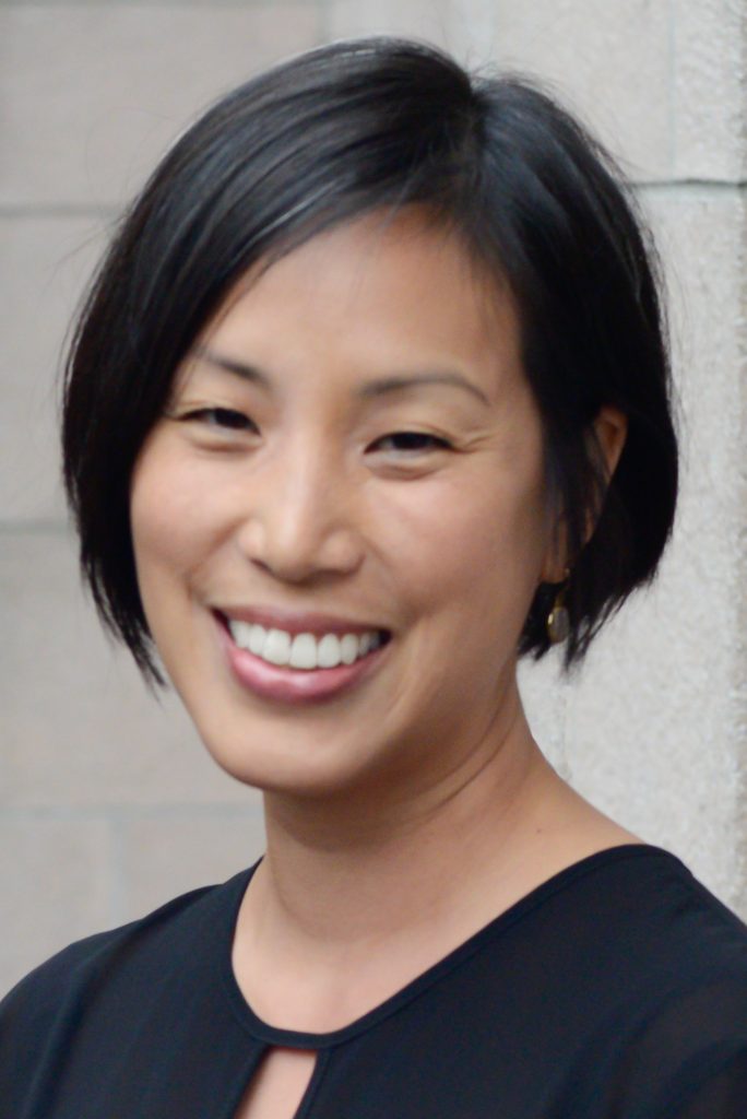 A smiling photo of Glenna Chang. Glenna has short black hair is wearing a black top.