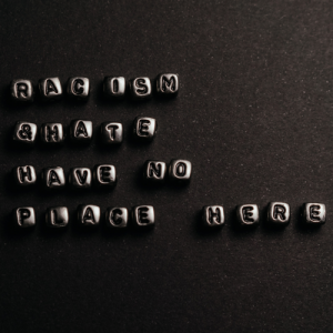 Letters created with typewriter keys spell out the message: "racism and hate have no place here" on a black background.