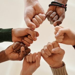 Hands of different skin tones touch each other in a circle.