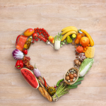 Multi-colored fruits and vegetables arranged in a heart shape.