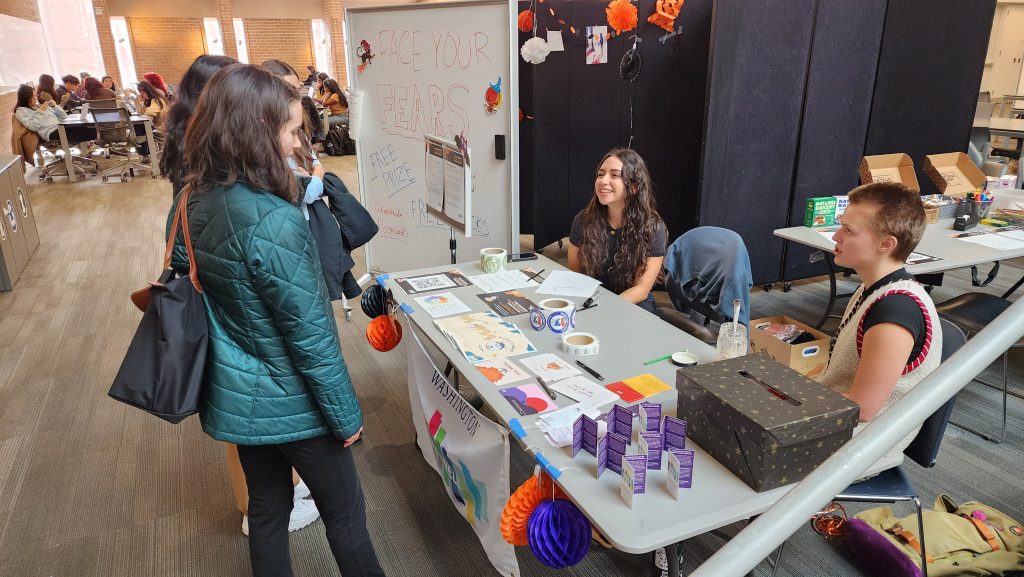 People talking to LiveWell Peer Health Educators at a tabling event